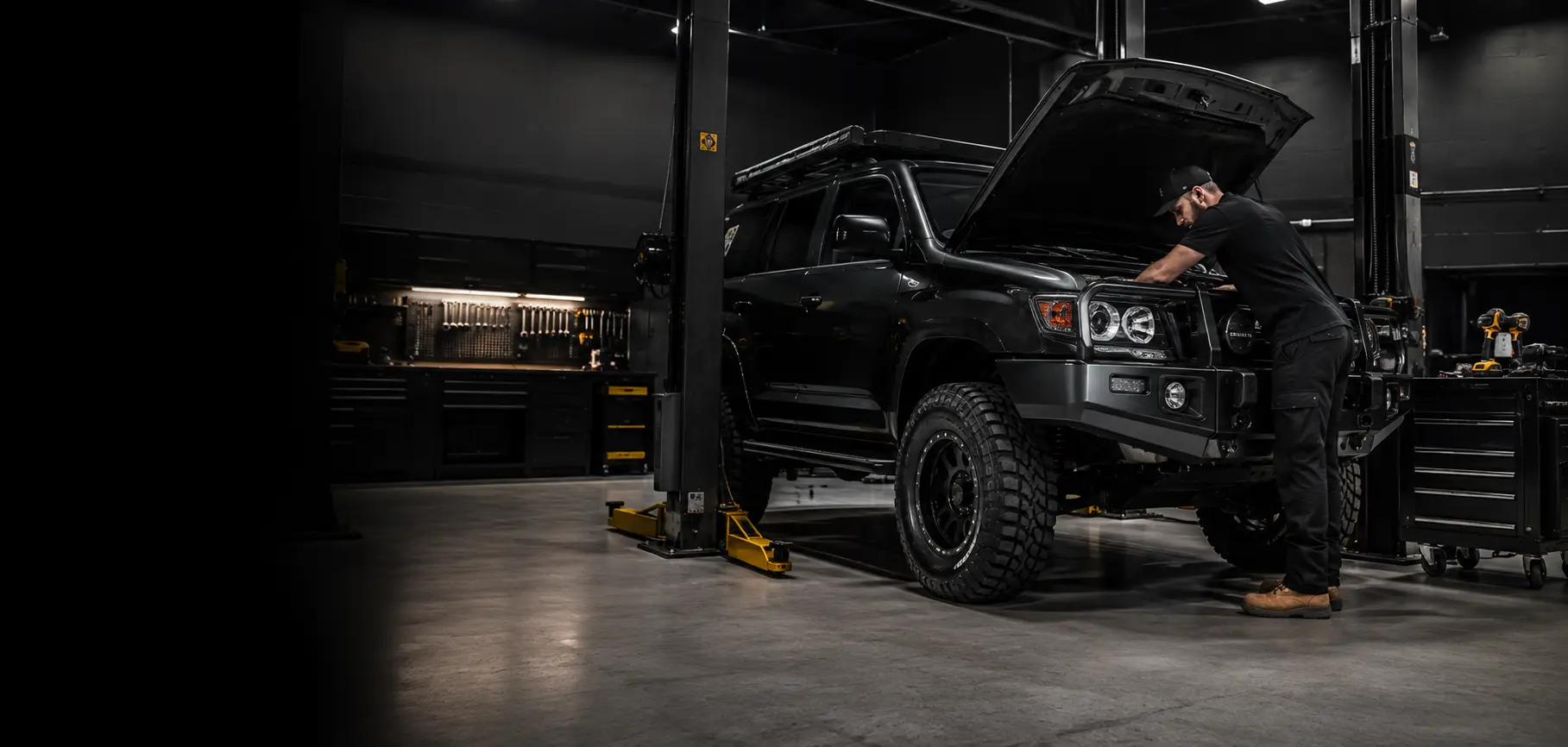 A mechanic inspecting a four-wheel drive in a modern workshop